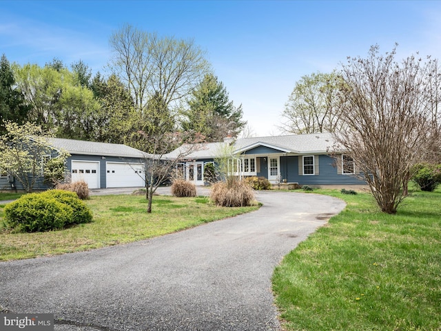 single story home featuring driveway, a front yard, and a garage