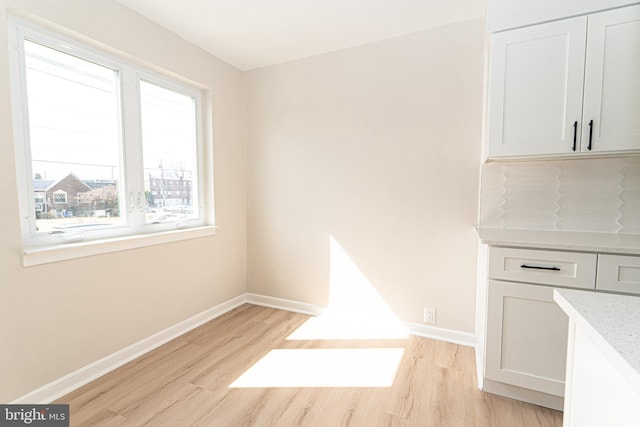 unfurnished dining area featuring baseboards and light wood finished floors