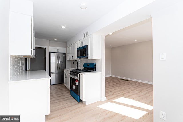 kitchen featuring tasteful backsplash, visible vents, appliances with stainless steel finishes, light countertops, and light wood-type flooring