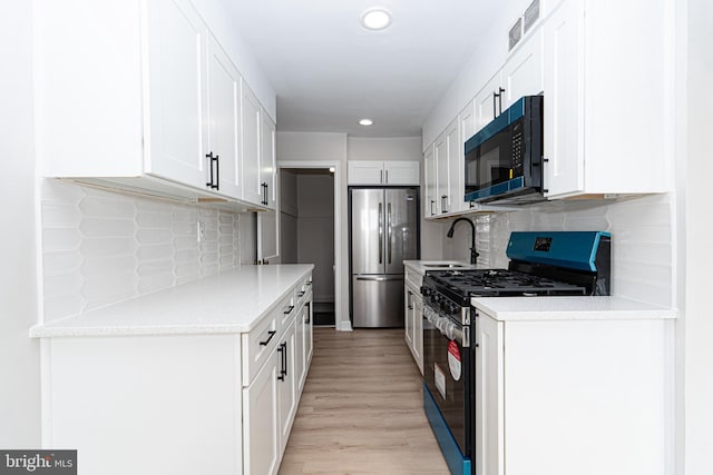 kitchen featuring visible vents, white cabinets, light wood-style flooring, appliances with stainless steel finishes, and a sink