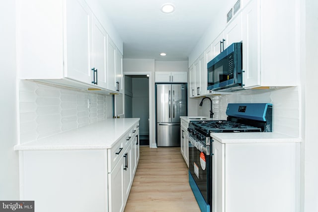 kitchen with visible vents, stainless steel appliances, light countertops, light wood-type flooring, and white cabinetry