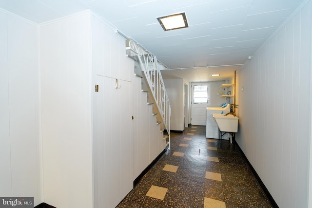 corridor featuring stairs, baseboards, and dark floors