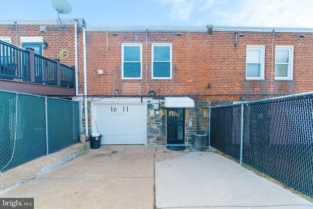 rear view of property featuring driveway, stone siding, fence, and brick siding