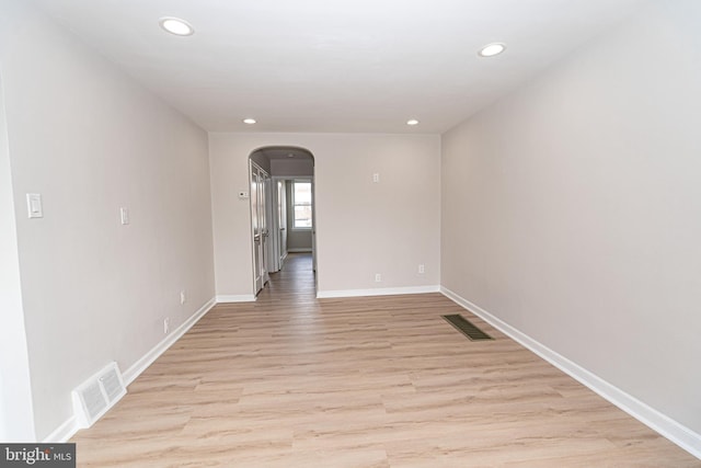 unfurnished room featuring arched walkways, visible vents, light wood-style flooring, and recessed lighting