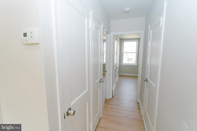 hall with light wood-type flooring and baseboards