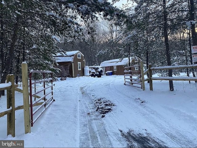 snowy yard featuring an outbuilding, fence, and a shed