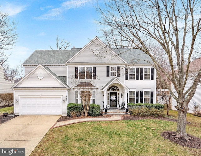 view of front of house featuring an attached garage, concrete driveway, roof with shingles, and a front yard