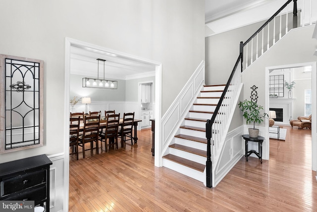 stairs featuring hardwood / wood-style flooring, ornamental molding, a decorative wall, and a glass covered fireplace