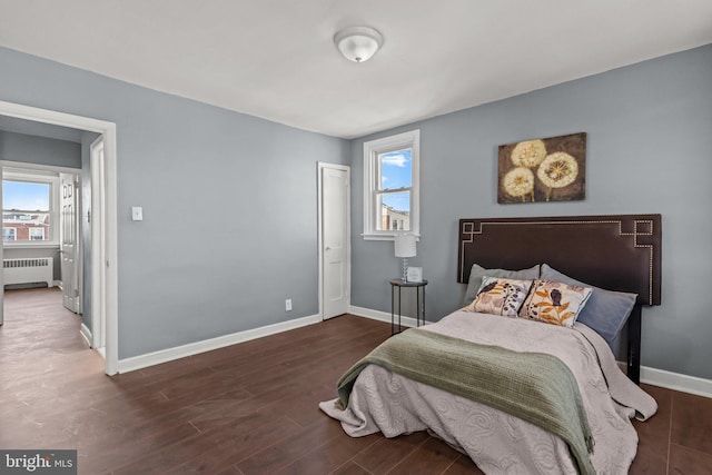 bedroom with baseboards, multiple windows, wood finished floors, and radiator heating unit