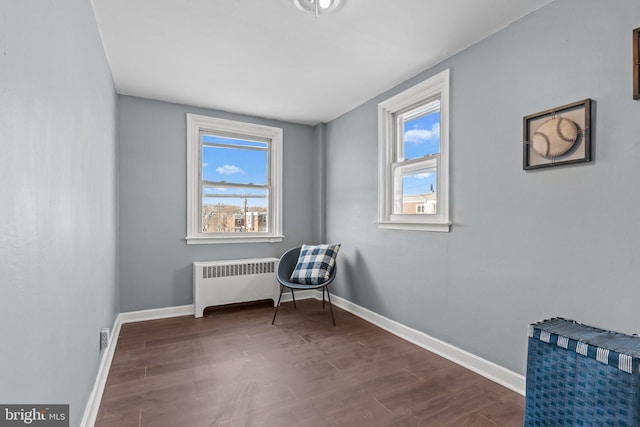 living area with radiator, baseboards, and dark wood-style flooring