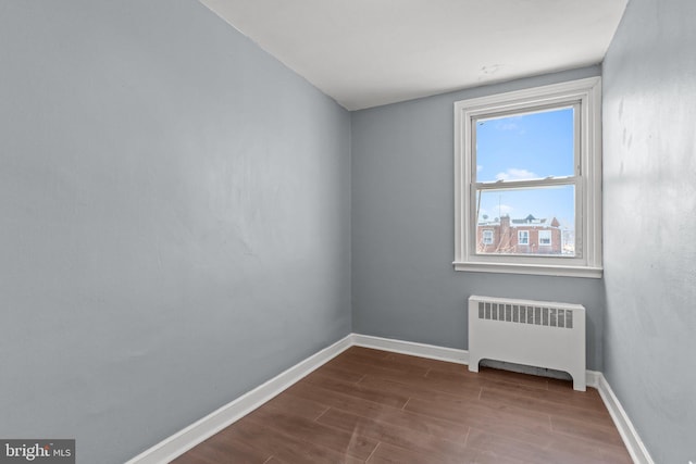 unfurnished room featuring baseboards, radiator, and dark wood-style flooring