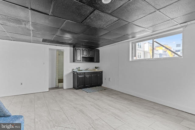 bar with a sink, baseboards, and a paneled ceiling