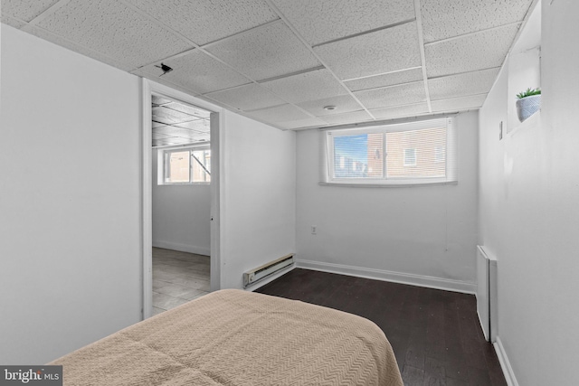 bedroom featuring a drop ceiling, a baseboard radiator, and baseboards