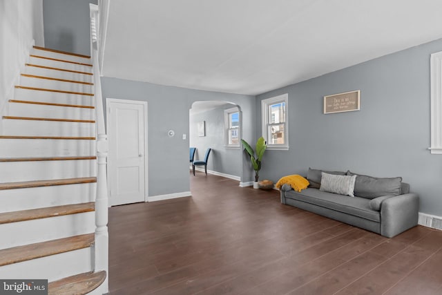 living area featuring stairs, visible vents, wood finished floors, and arched walkways