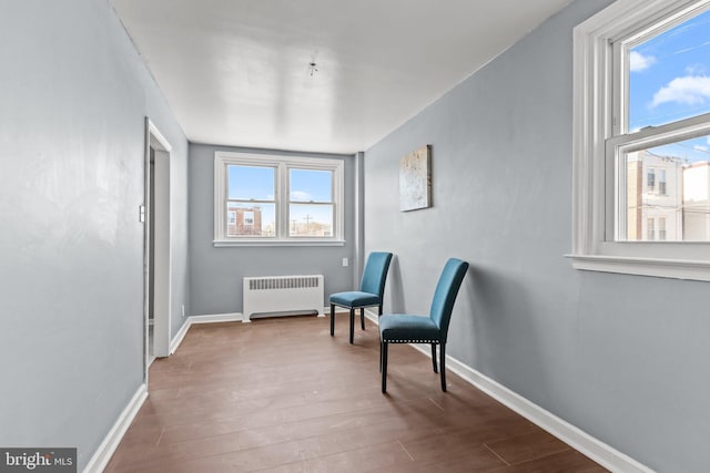 sitting room featuring radiator, dark wood-style floors, plenty of natural light, and baseboards