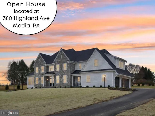 view of front of property with stone siding, a lawn, driveway, and an attached garage