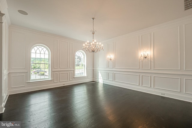 spare room with a chandelier, a decorative wall, dark wood-style flooring, and ornamental molding