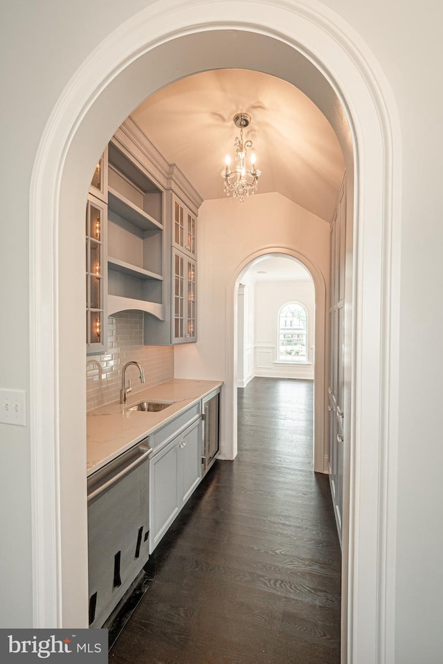 kitchen featuring dishwasher, dark wood-type flooring, vaulted ceiling, light countertops, and a sink