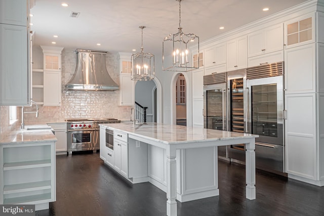 kitchen with visible vents, white cabinets, premium appliances, wall chimney exhaust hood, and open shelves