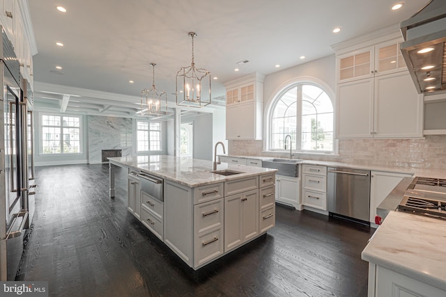 kitchen featuring a sink, stainless steel dishwasher, a warming drawer, dark wood finished floors, and a center island with sink