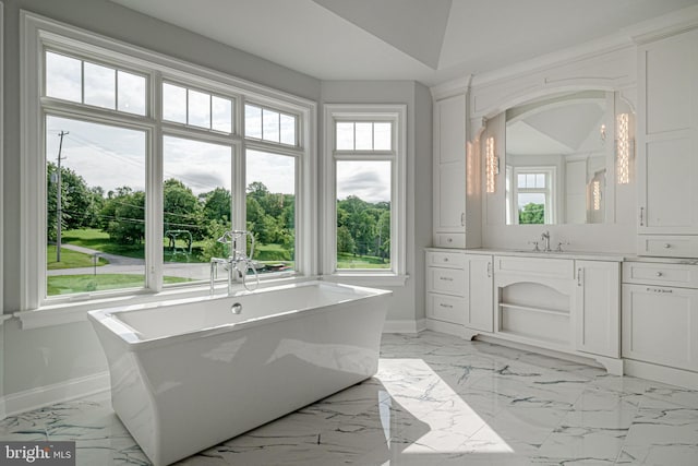 bathroom featuring a freestanding bath, marble finish floor, vanity, and baseboards