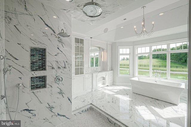 full bath with a healthy amount of sunlight, marble finish floor, a tile shower, and an inviting chandelier