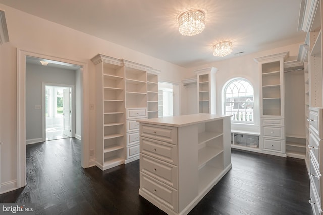 spacious closet featuring dark wood-type flooring and an inviting chandelier