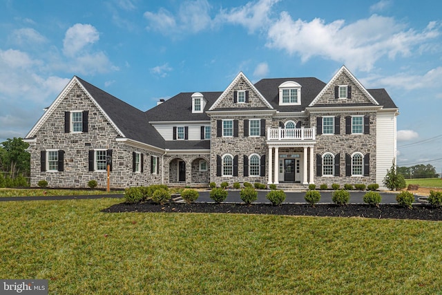 view of front facade featuring a front yard and a balcony