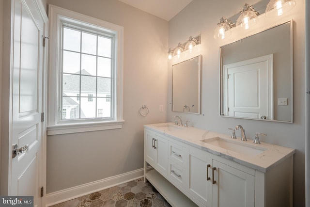 bathroom with double vanity, a sink, and baseboards