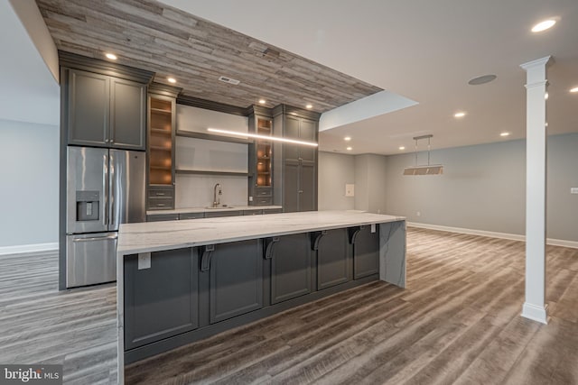 kitchen with wood finished floors, a sink, baseboards, a large island, and stainless steel refrigerator with ice dispenser