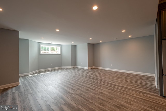 empty room with dark wood-type flooring, recessed lighting, and baseboards