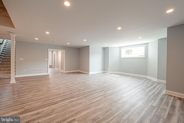 unfurnished living room featuring recessed lighting, visible vents, baseboards, light wood-style floors, and stairway