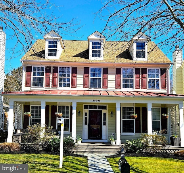 view of front facade featuring covered porch, a front yard, a standing seam roof, and metal roof