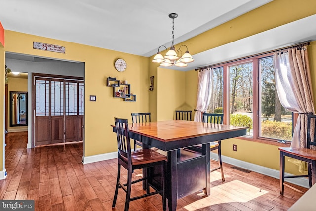 dining space featuring visible vents, baseboards, an inviting chandelier, and wood-type flooring