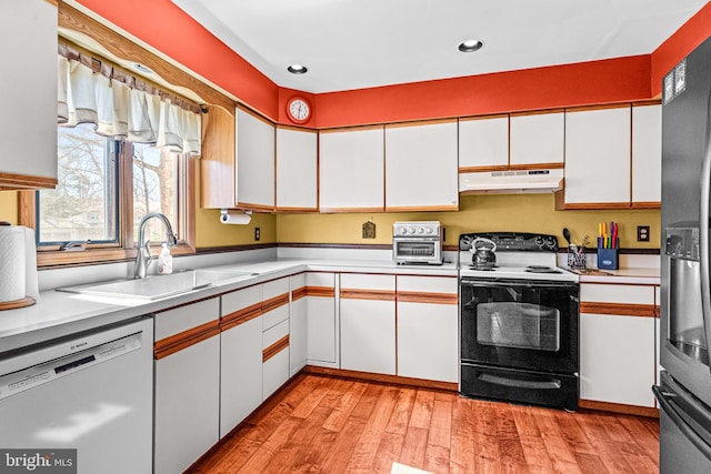 kitchen featuring under cabinet range hood, stainless steel dishwasher, electric range, white cabinetry, and a sink