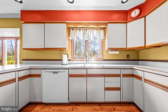 kitchen featuring dishwasher, white cabinets, a healthy amount of sunlight, and a sink