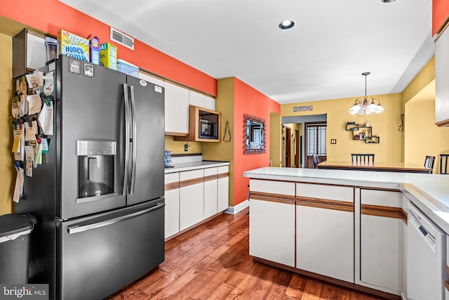 kitchen featuring visible vents, stainless steel fridge with ice dispenser, dishwasher, wood finished floors, and white cabinetry