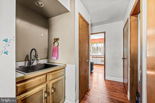 interior space featuring light countertops, wood-type flooring, baseboards, and a sink