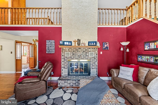 living room featuring baseboards, a high ceiling, wood finished floors, and a fireplace