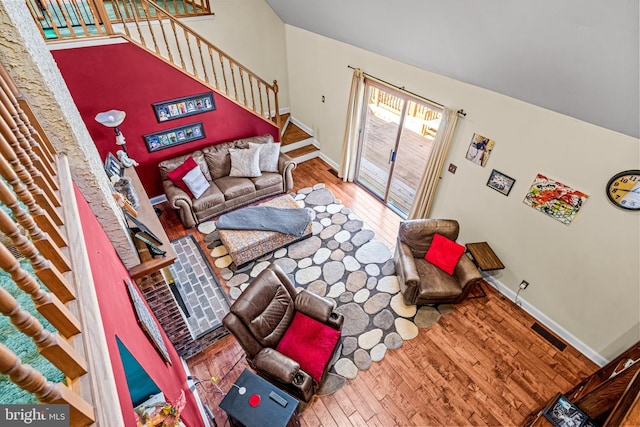 living area with visible vents, stairs, baseboards, and wood finished floors