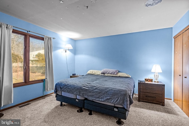 bedroom with a closet, visible vents, carpet flooring, and baseboards