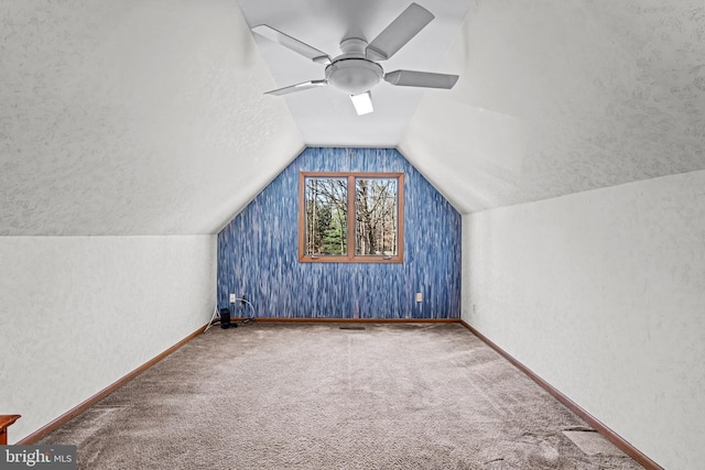 additional living space featuring baseboards, carpet floors, vaulted ceiling, a textured ceiling, and a ceiling fan