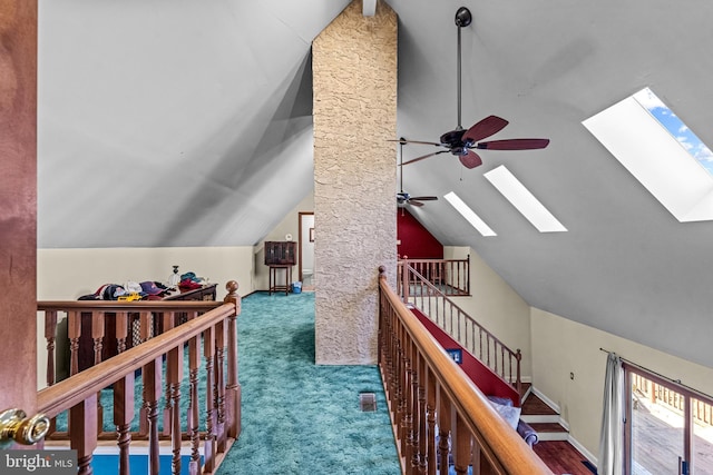 hall featuring baseboards, an upstairs landing, carpet, and vaulted ceiling with skylight