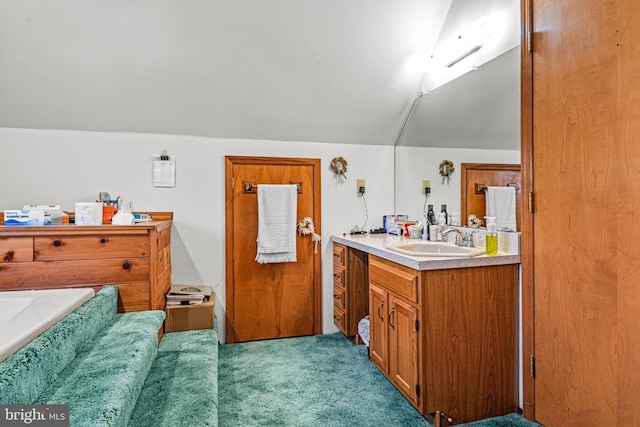 bathroom featuring a bath, vanity, and lofted ceiling