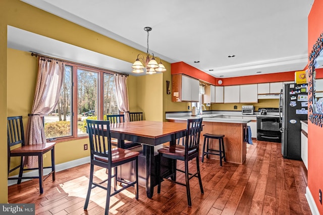 dining room with a toaster, baseboards, an inviting chandelier, and hardwood / wood-style floors