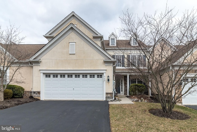 traditional-style home featuring an attached garage, aphalt driveway, and stucco siding