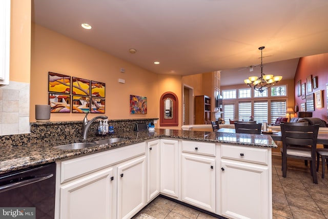 kitchen featuring a notable chandelier, a sink, white cabinetry, dishwasher, and dark stone countertops