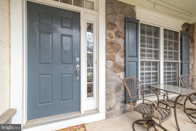 entrance to property with stone siding and a porch