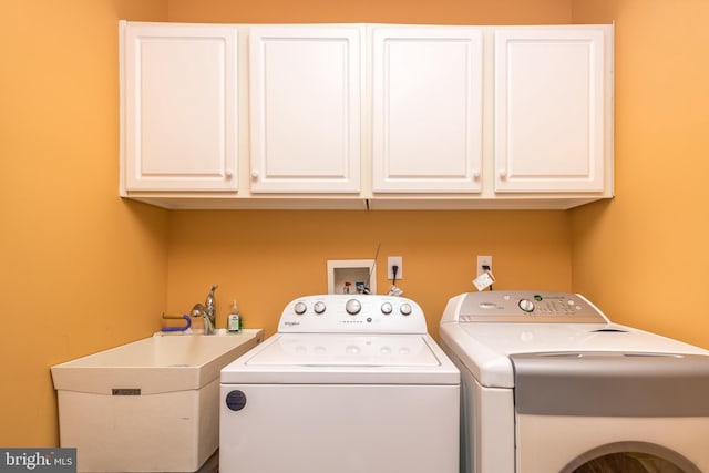 laundry area featuring separate washer and dryer, a sink, and cabinet space