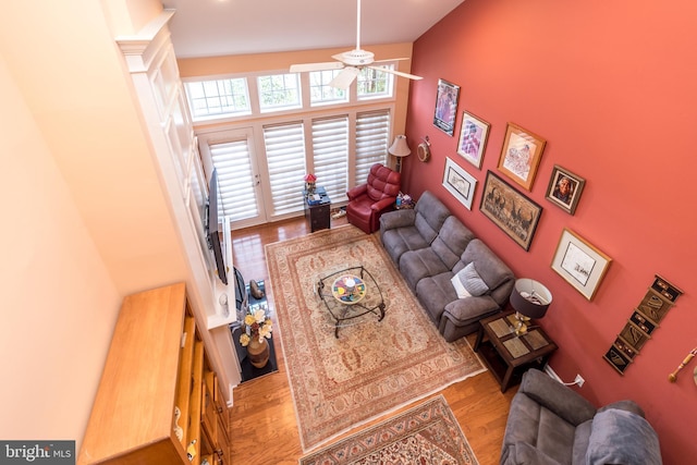 living area with ceiling fan, high vaulted ceiling, and wood finished floors